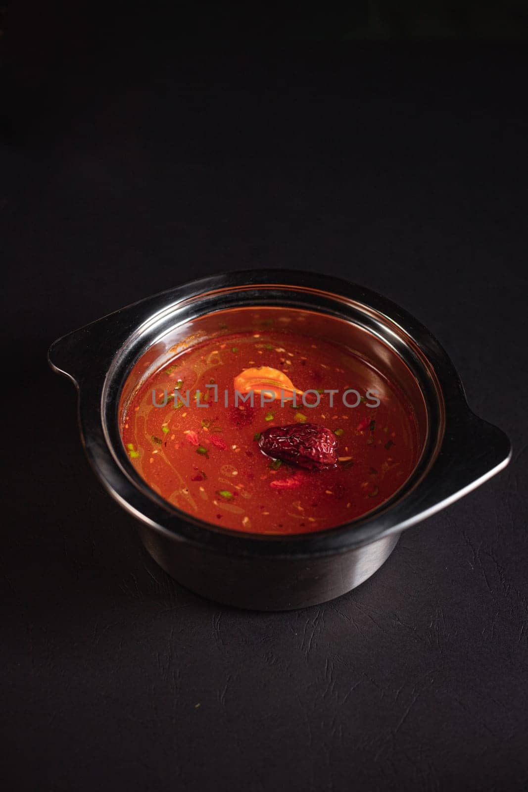 soup broth in an iron plate on a dark background side view by tewolf