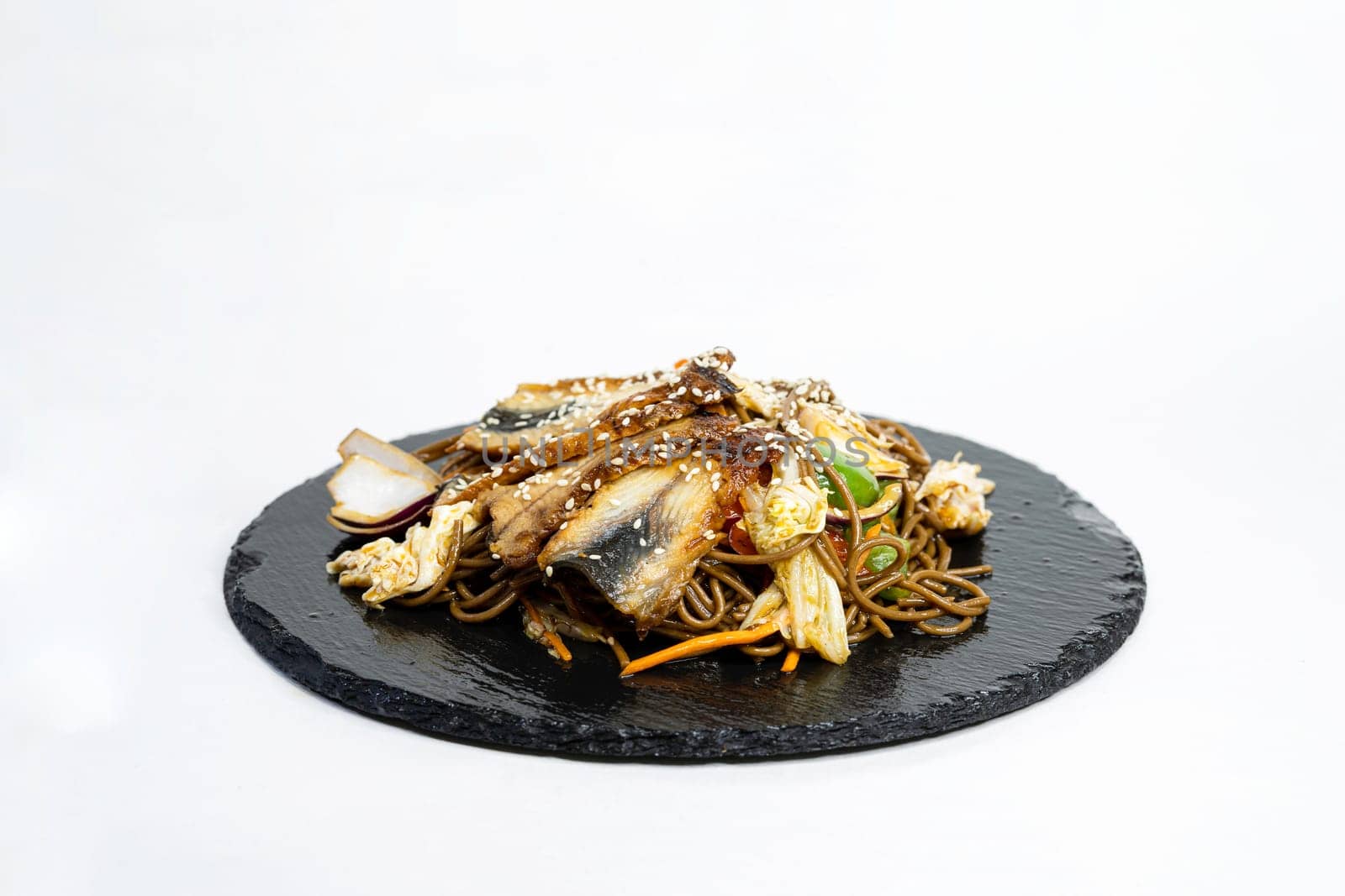 fried noodles with vegetables and meat in a flat plate on a white background