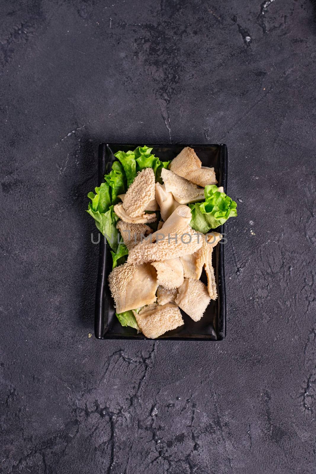 sliced boiled meat on a black plate on a white background