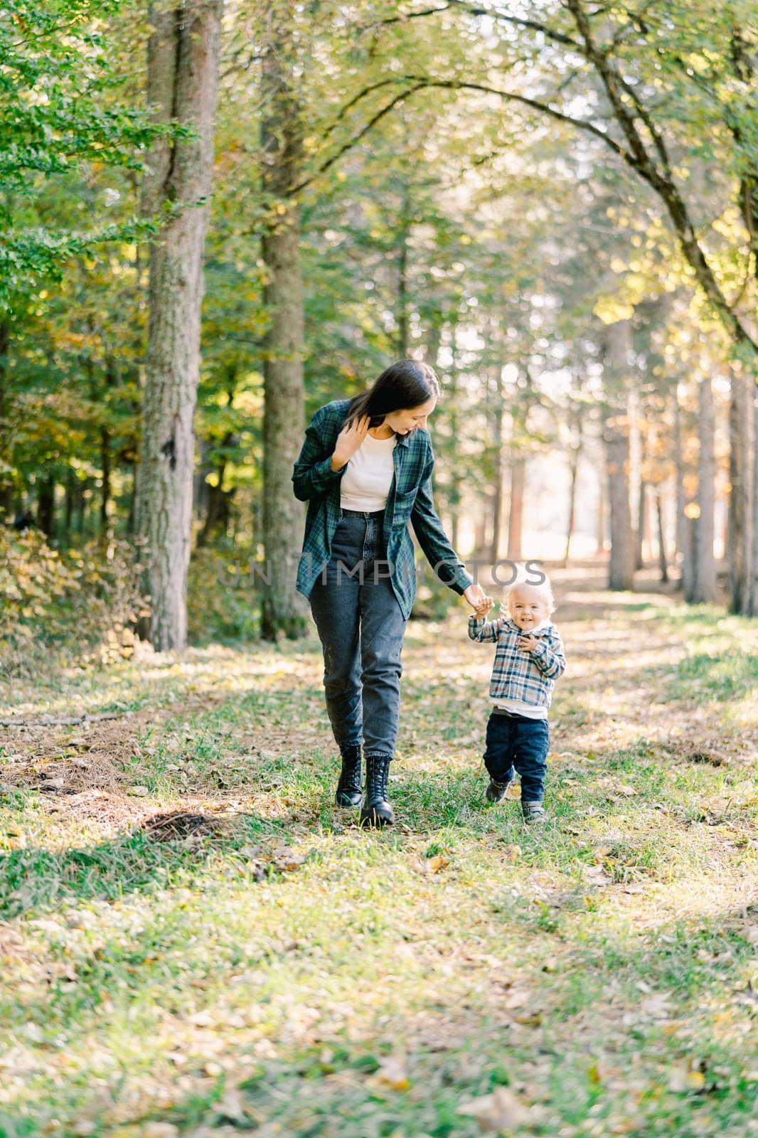 Mom and little girl walk holding hands in the park. High quality photo