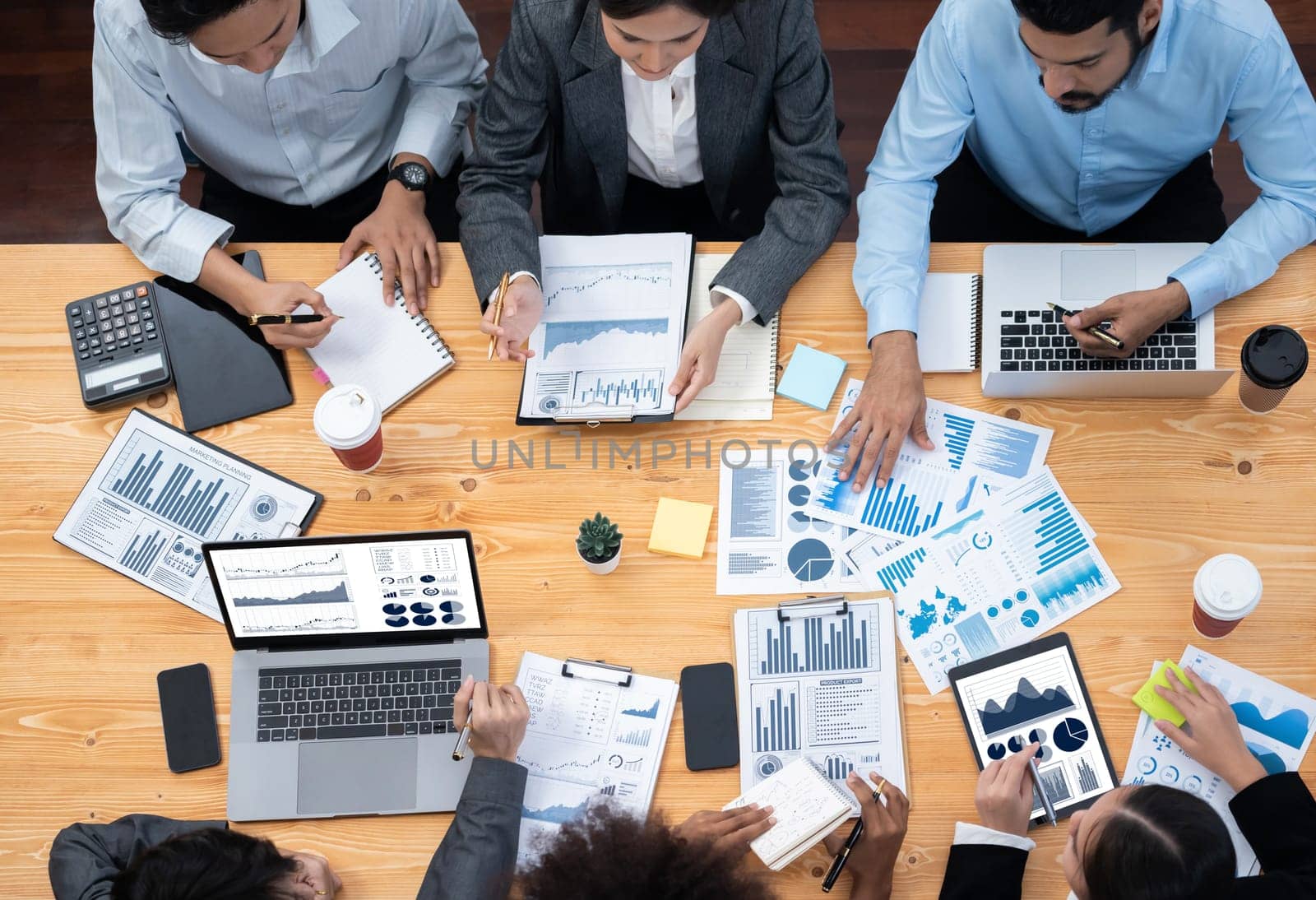 Top view multiracial analyst team use BI dashboard data to analyze financial report on meeting table. Group of diverse business people utilize data analysis by FIntech for business decision. Concord