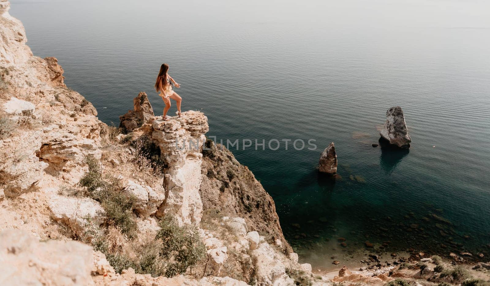 Woman travel sea. Happy tourist taking picture outdoors for memories. Woman traveler looks at the edge of the cliff on the sea bay of mountains, sharing travel adventure journey.