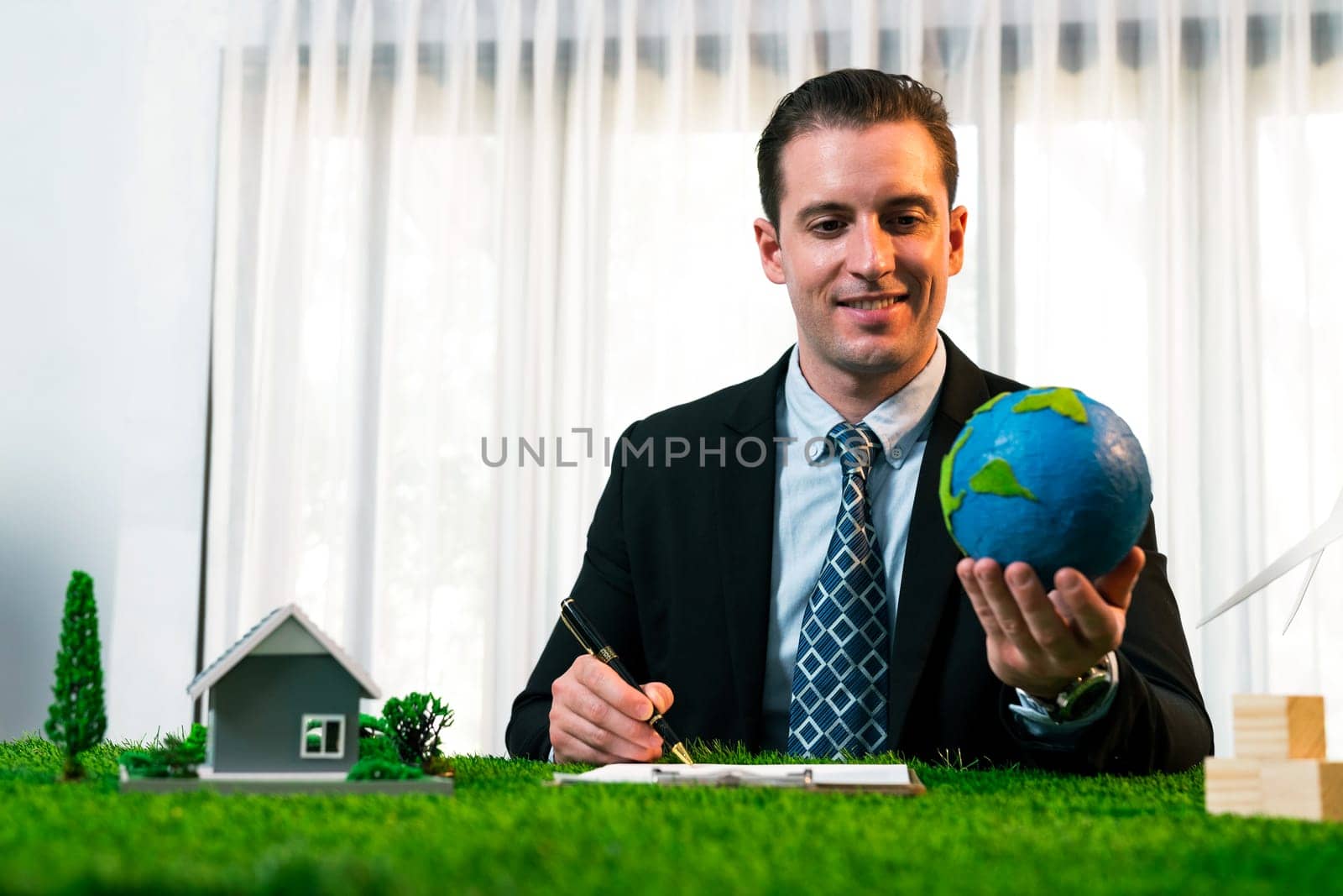 Eco business and save Earth concept shown by businessman or CEO holding paper globe in office with eco friendly mockup to promote CO2 and carbon footprint reduction for greener future. Quaint