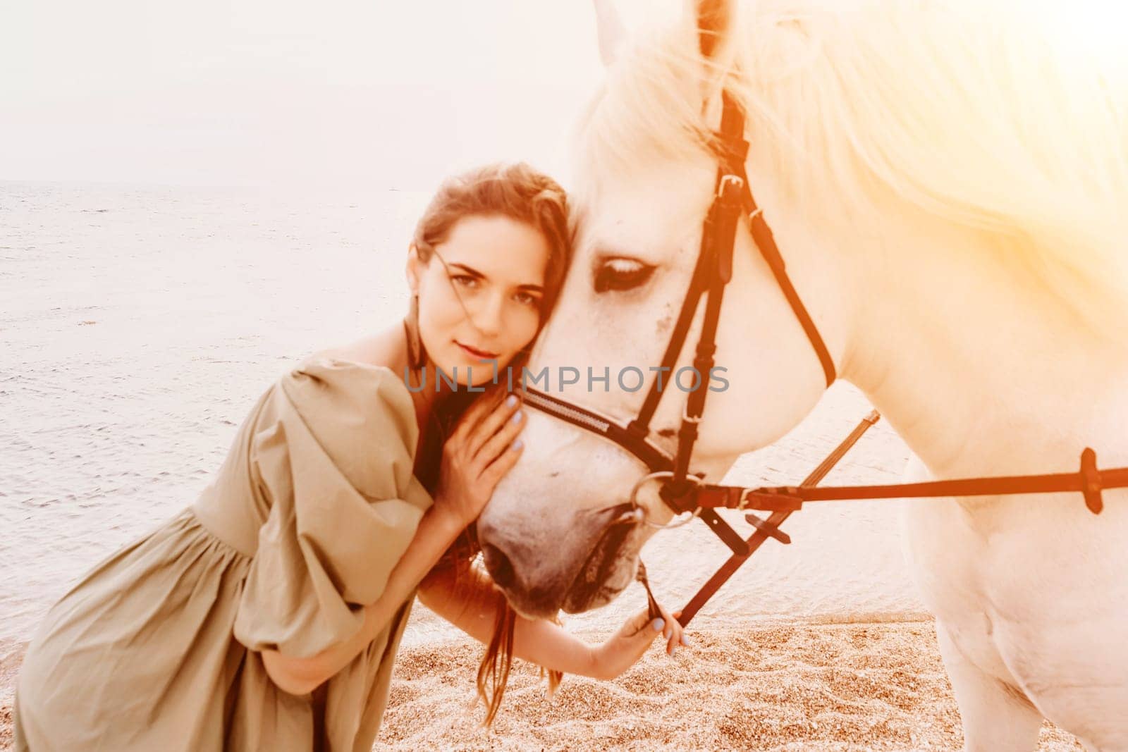 A white horse and a woman in a dress stand on a beach, with the sky and sea creating a picturesque backdrop for the scene