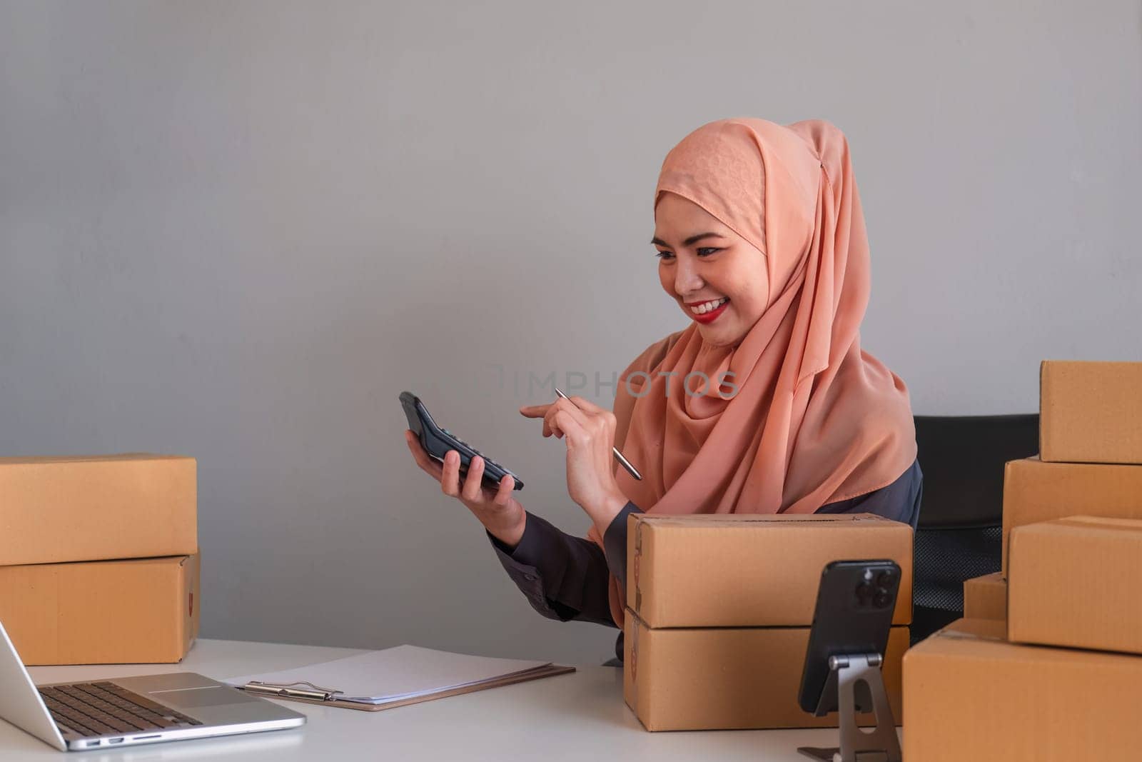 Asian Muslim businesswoman checks stock orders and saves them on her home office laptop. small business owner Shipping in online markets The concept of freedom in life by wichayada