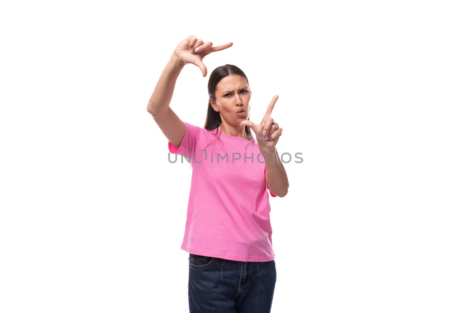 young positive good-looking woman with black hair dressed in a pink t-shirt makes a frame from her hands.