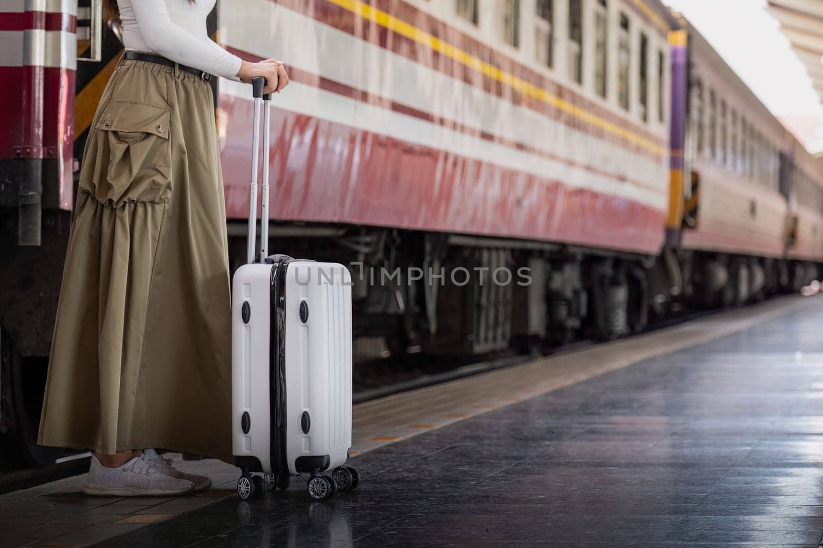 Alone Asian woman traveler with suitcase in train station platform. Summer vacation holiday and travel concept by nateemee