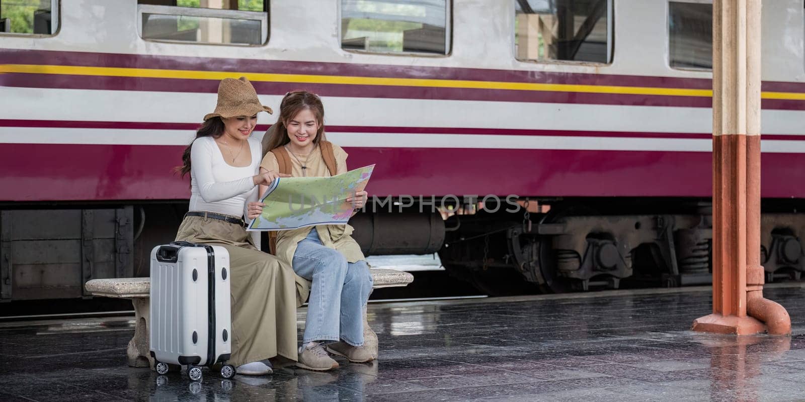 Travel concept. girl friend wear hat holding map have bag and luggage. female traveller waiting train at train station by nateemee