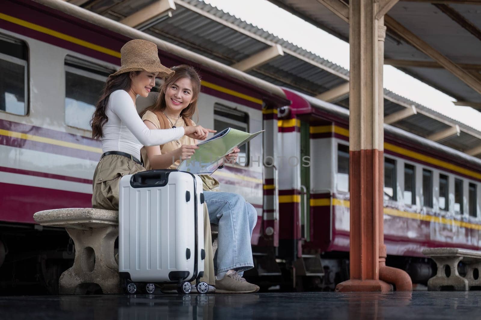 Travel concept. girl friend wear hat holding map have bag and luggage. female traveller waiting train at train station.