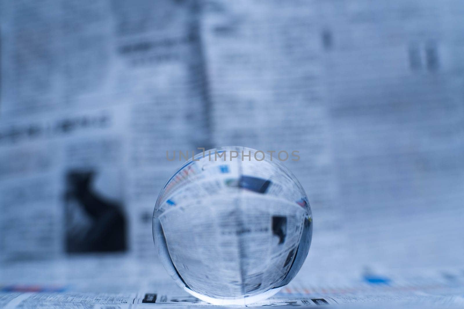 A glass globe reveals the letters inside, with a newspaper in the background.