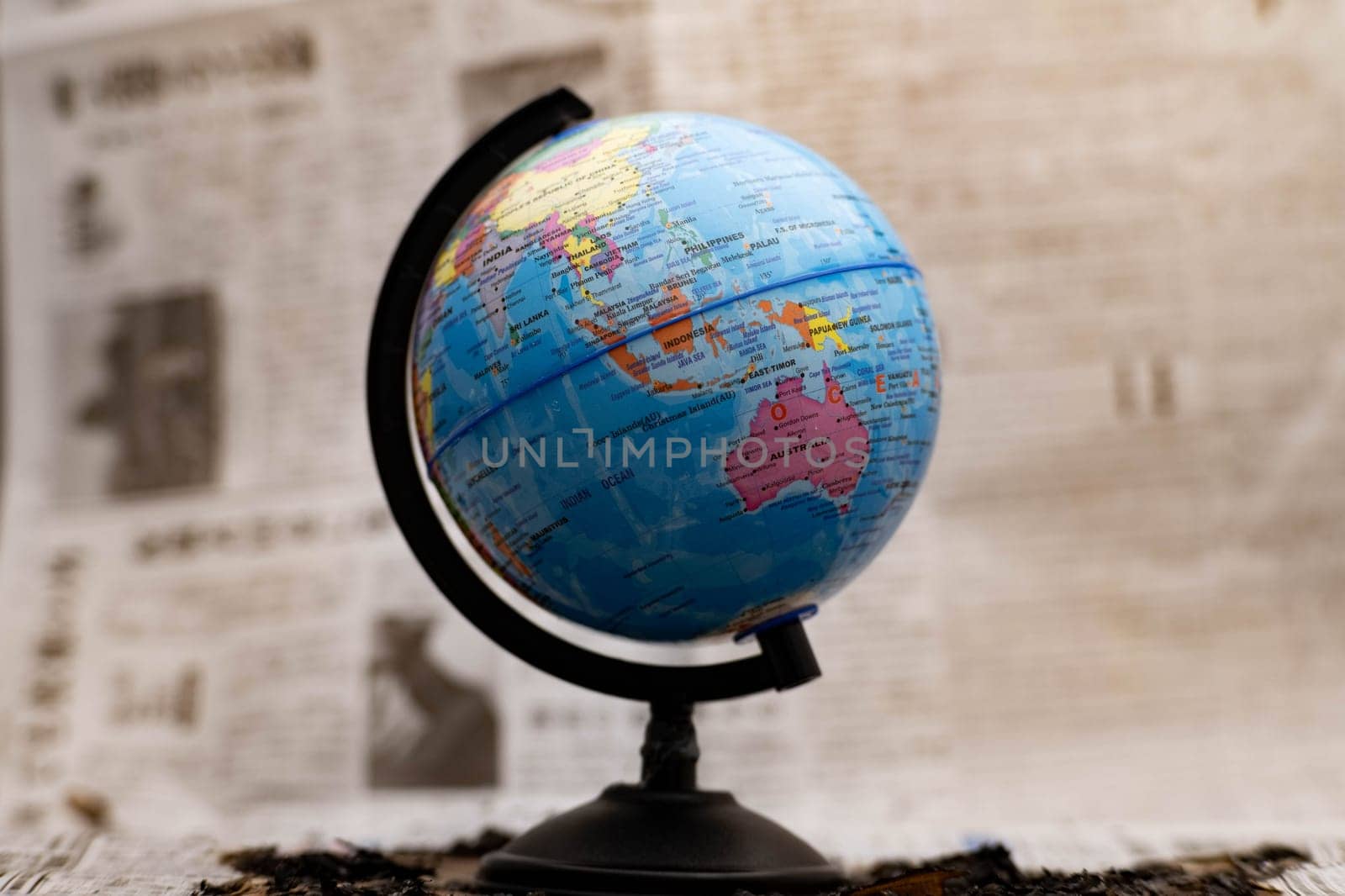 Model globe on a newspaper in the background. by TEERASAK