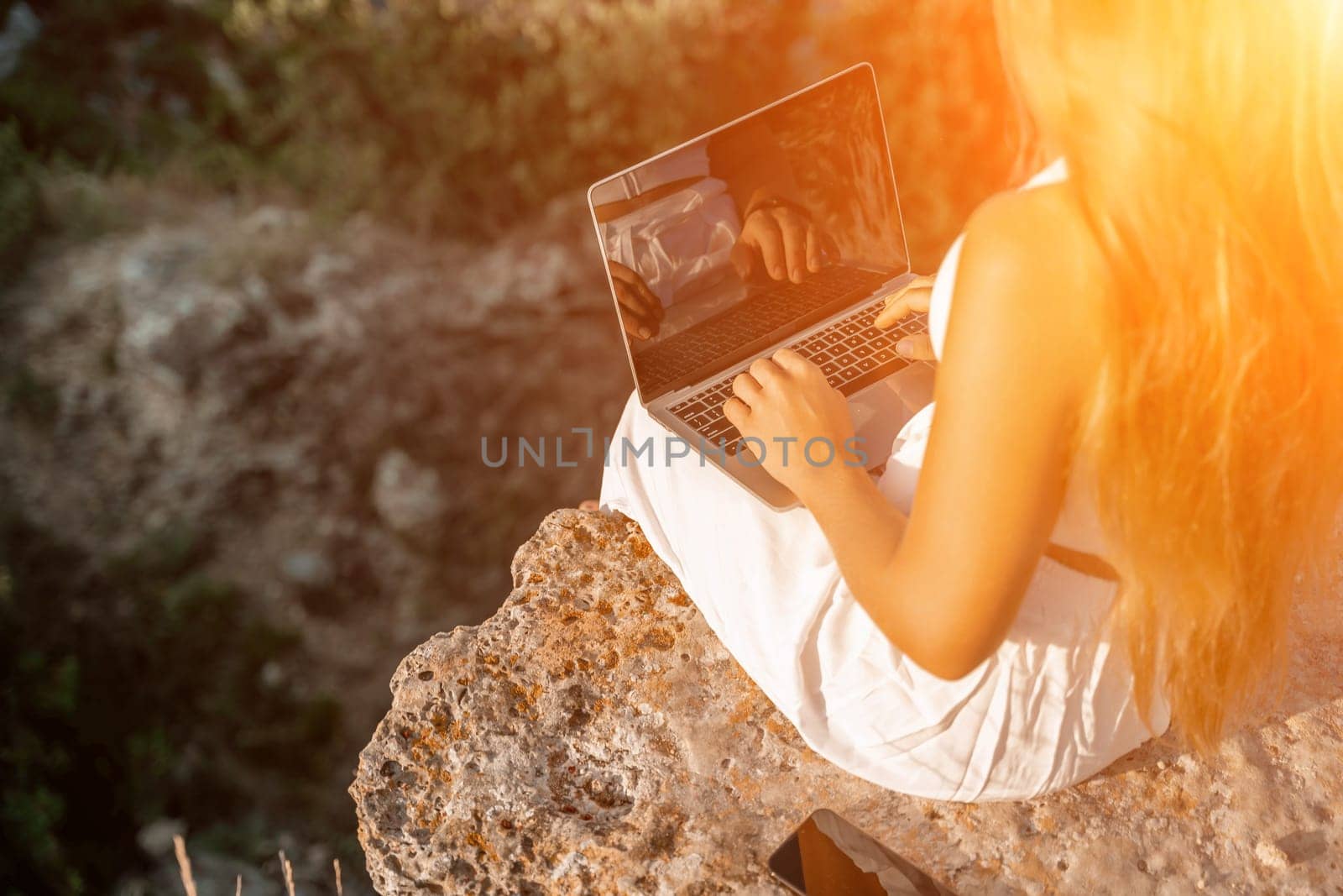 Freelance happy woman typing on her laptop, enjoying the picturesque sea view, highlighting the idea of working remotely with a relaxed and pleasant atmosphere. by Matiunina