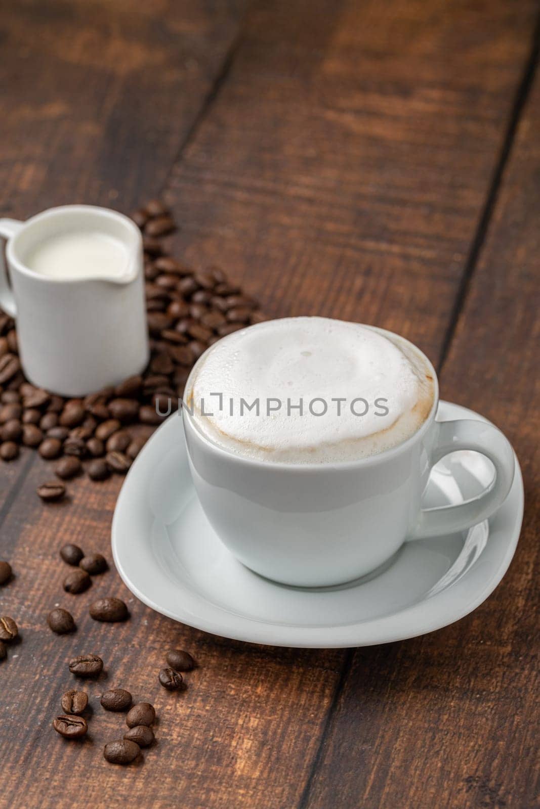Cappuccino coffee in a white porcelain cup on a wooden table by Sonat