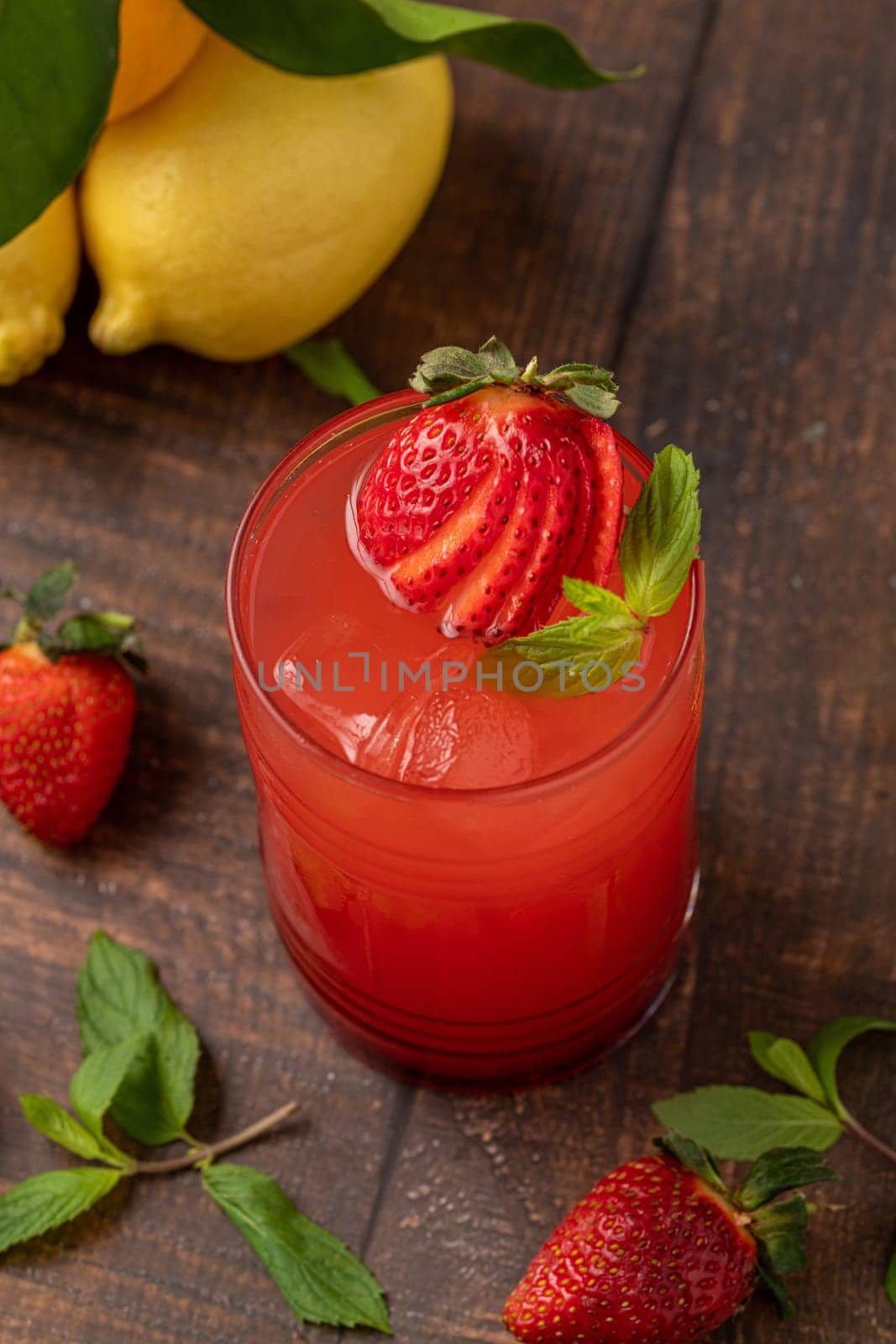 Iced strawberry lemonade in glass glass on wooden table by Sonat