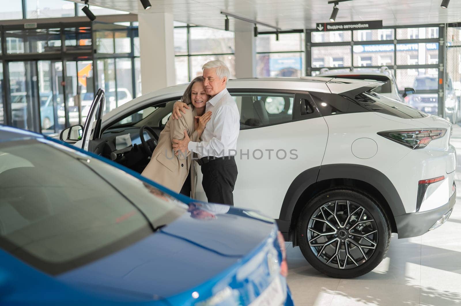 Mature Caucasian couple hugging with happiness while buying a new car. by mrwed54