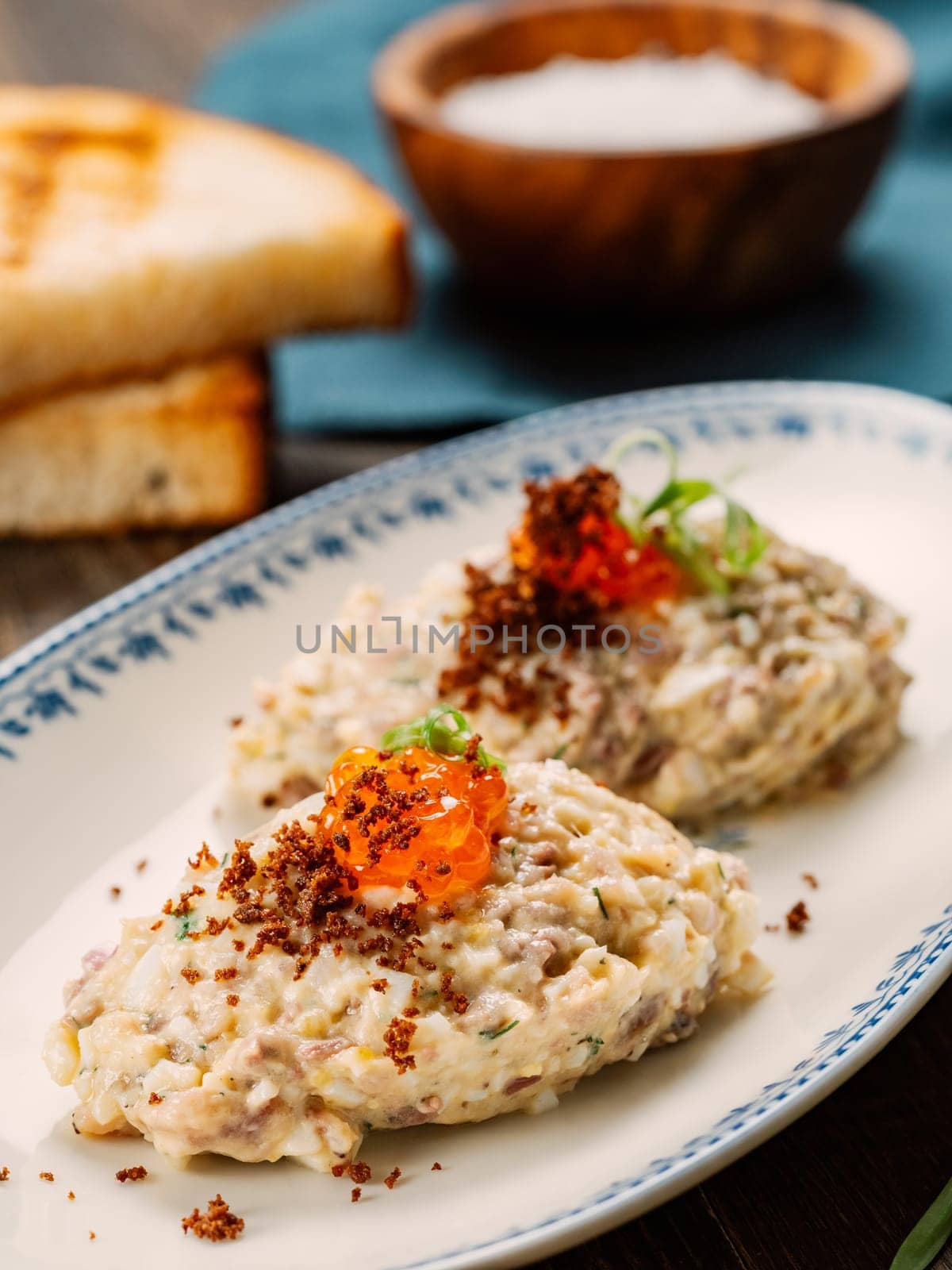 Fish appetizer forshmak - minced meat from herring fish, decorated caviar on plate. Traditional Jewish cuisine dish vorschmack forshmak made of herring fillet as independent dish on wooden background