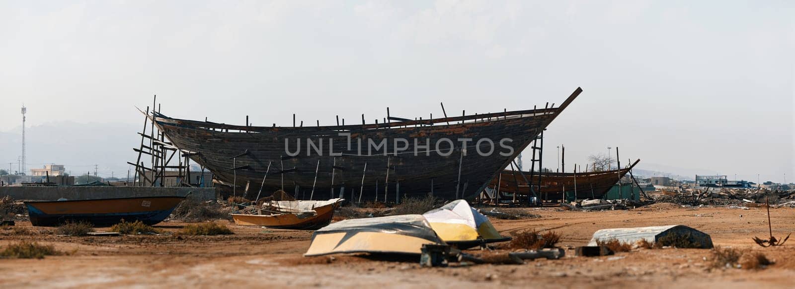 Construction of a wooden ship. Shipyard of traditional Dhow wooden boat on Iranian Qeshm Island. Tradition Lenj Fishing Boat in Qeshm Island in Southern Iran. Old wooden stealth smuggler's ship by EvgeniyQW