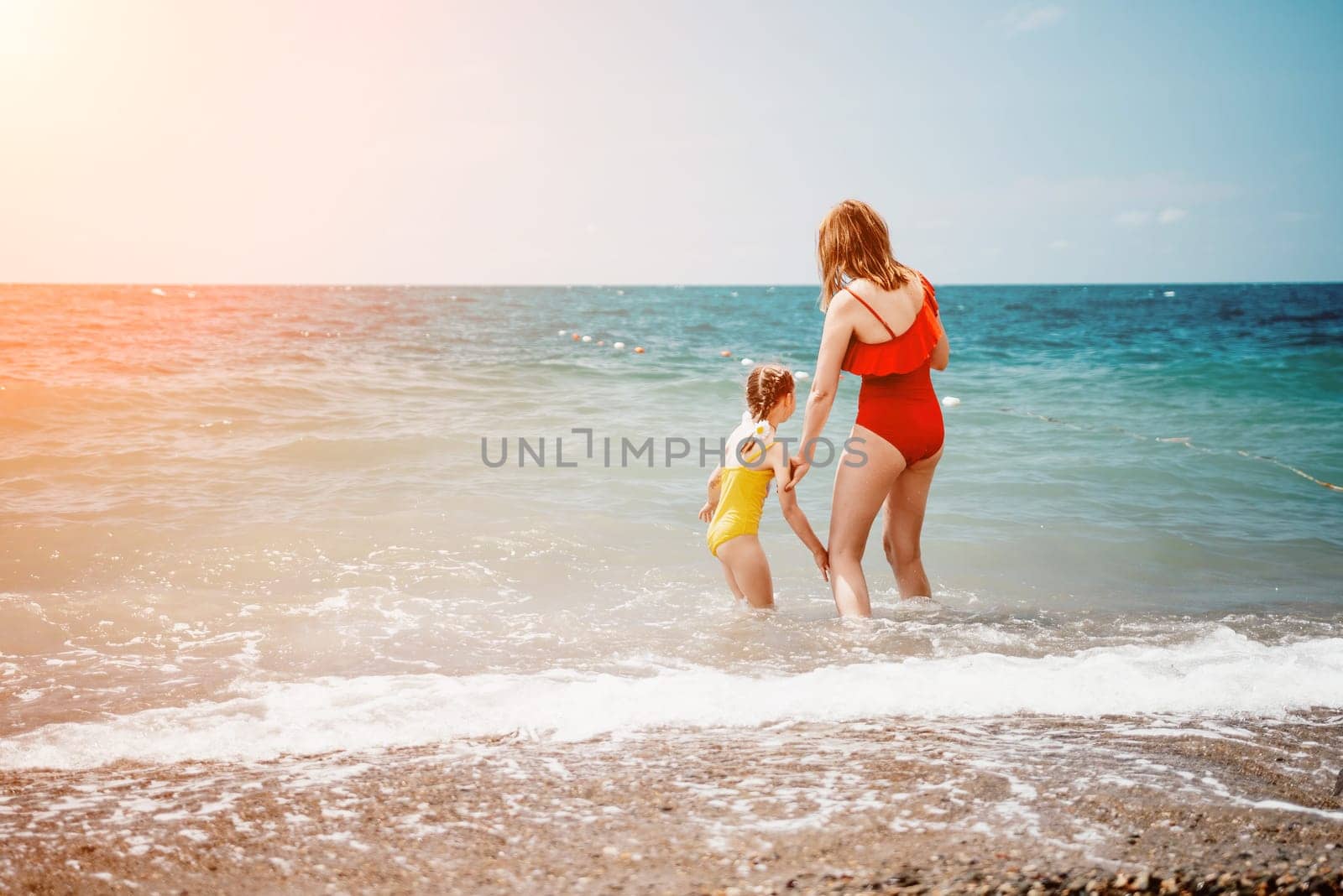 Happy loving family mother and daughter having fun together on the beach. Mum playing with her kid in holiday vacation next to the ocean - Family lifestyle and love concept by panophotograph