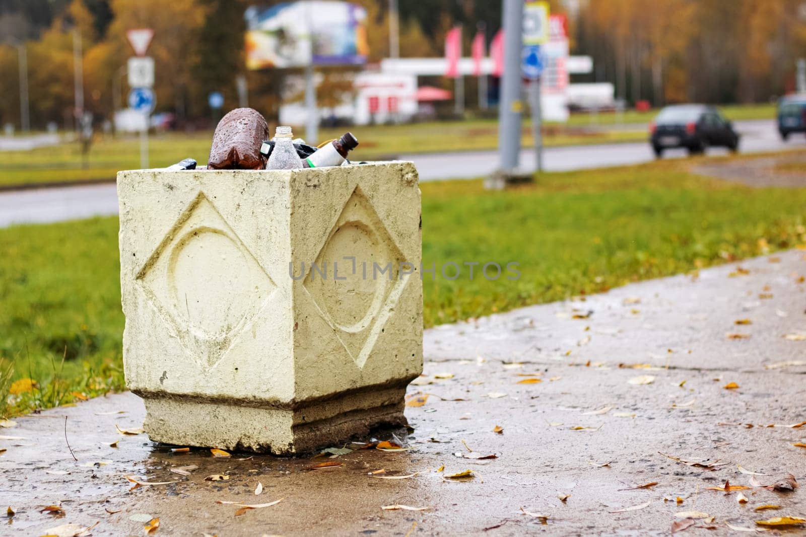 Concrete trash bin with empty bottles on the road background