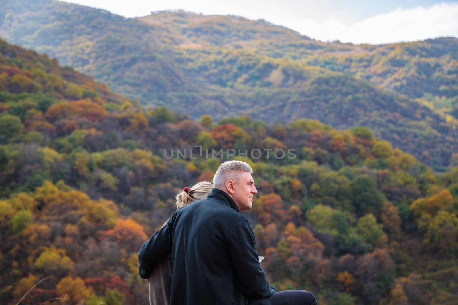 Loving couple in the mountains enjoying the scenery in their arms by Yurich32
