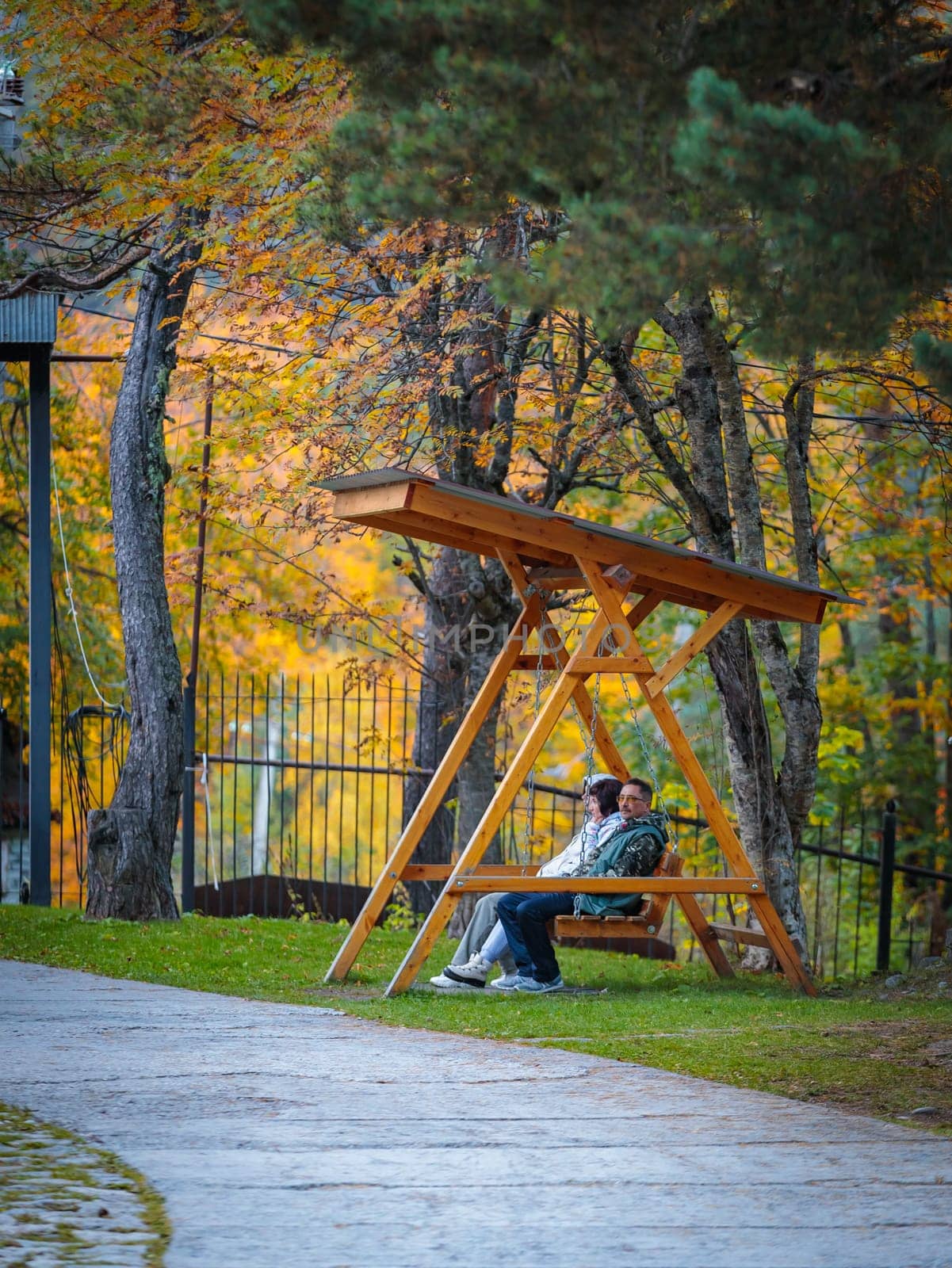 Cute couple enjoying bright autumn colors while relaxing on park bench by Yurich32