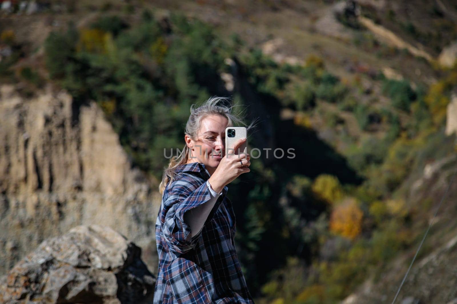 Young photographer enjoying the view of a mountain gorge, capturing it in the camera lens