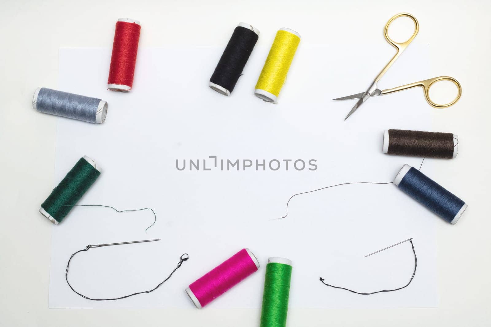 Frame of colorful threads, needles and scissors on white background, background
