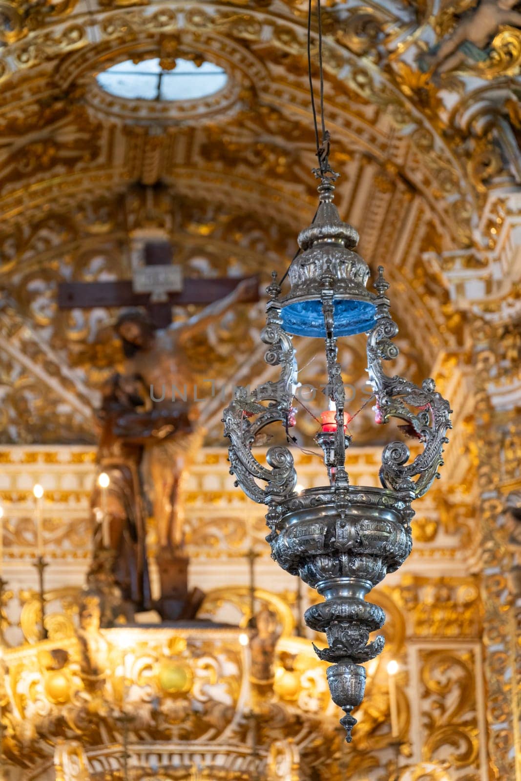 Silver lamp detailed against church's ornate golden interior.
