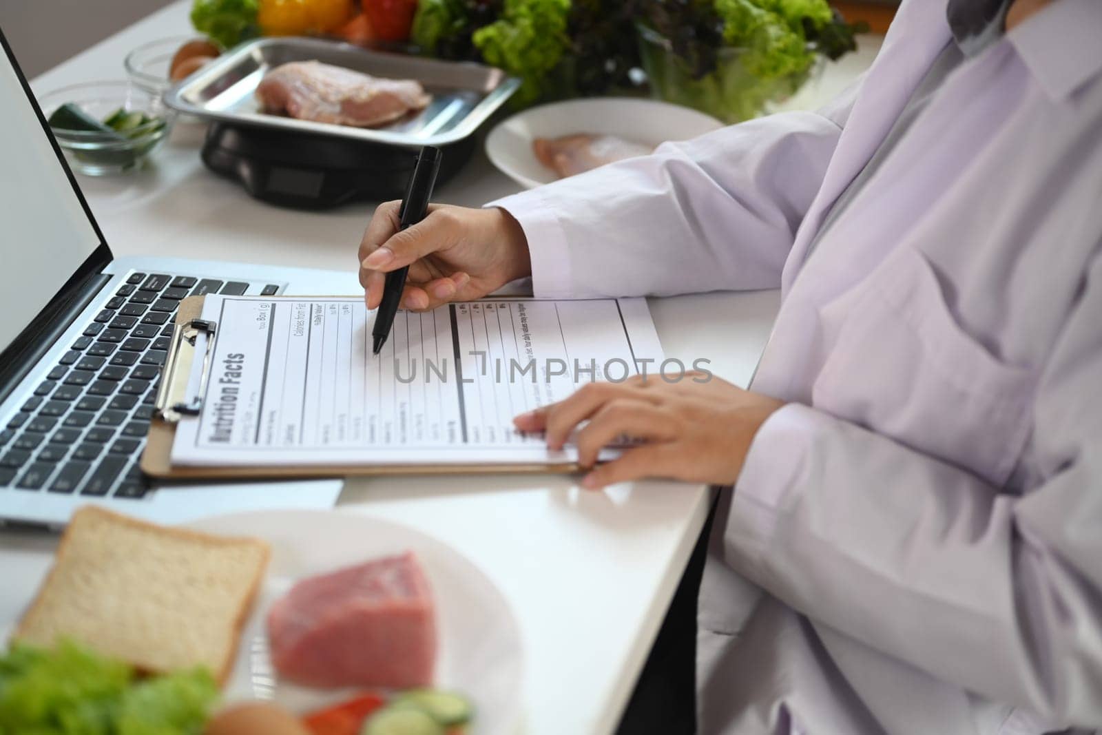 Cropped shot dietician working at desk with various healthy products. Healthy eating concept.