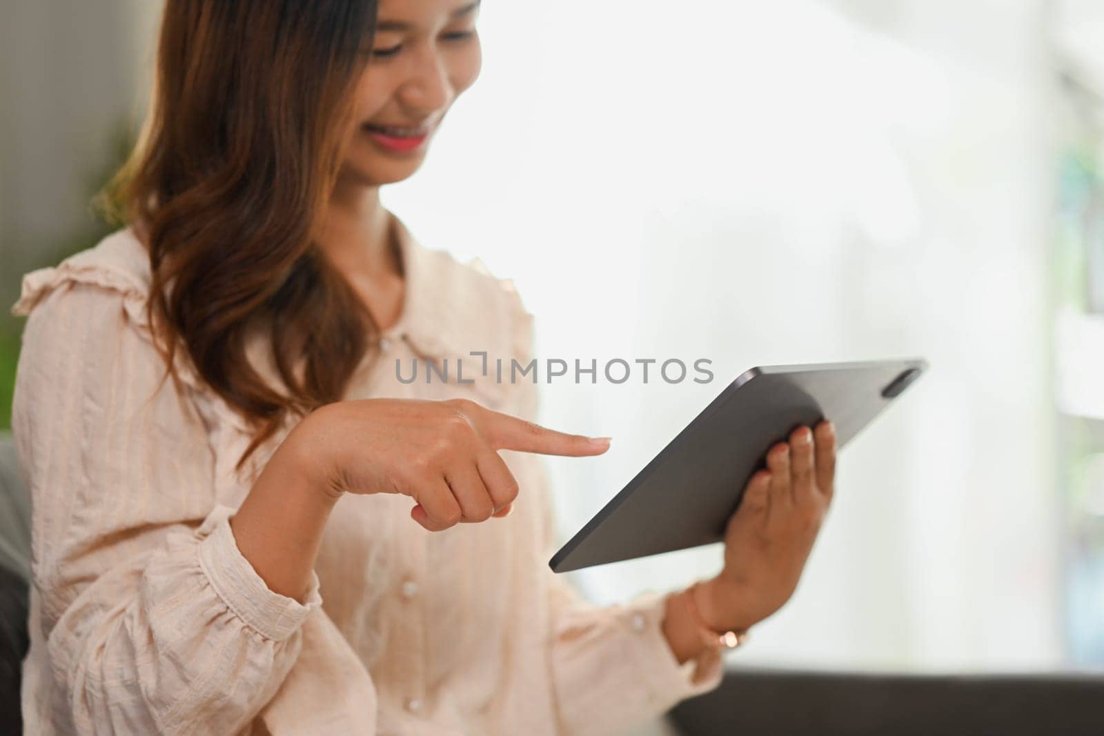Pretty young woman browsing internet on digital tablet. People and technology concept.