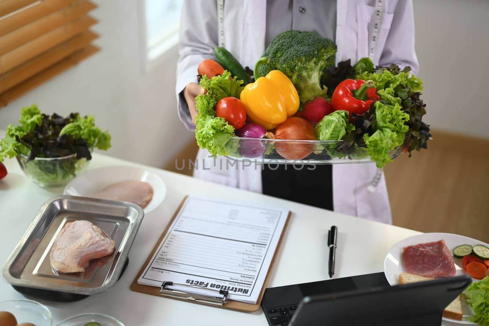 Nutritionist in white coat holding a bowl of vegetables for healthy eating and diet