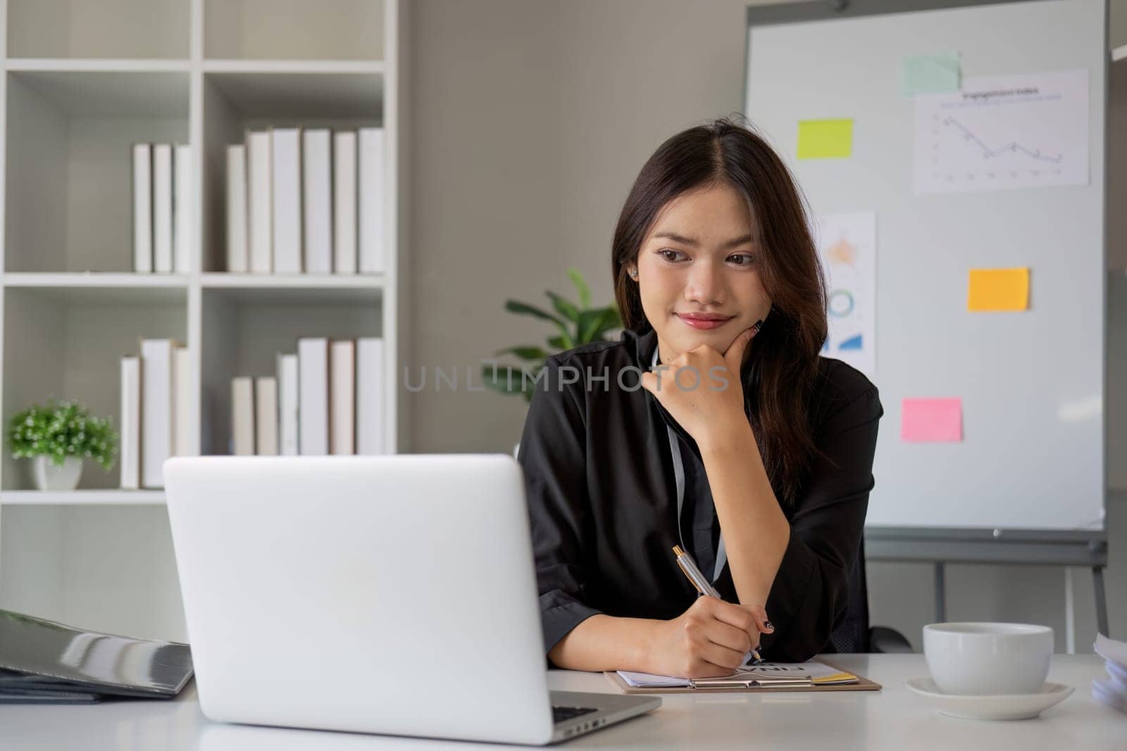 Portrait of young Asian woman working on laptop in modern office Perform accounting analysis, report investment data. Financial concepts and tax system.