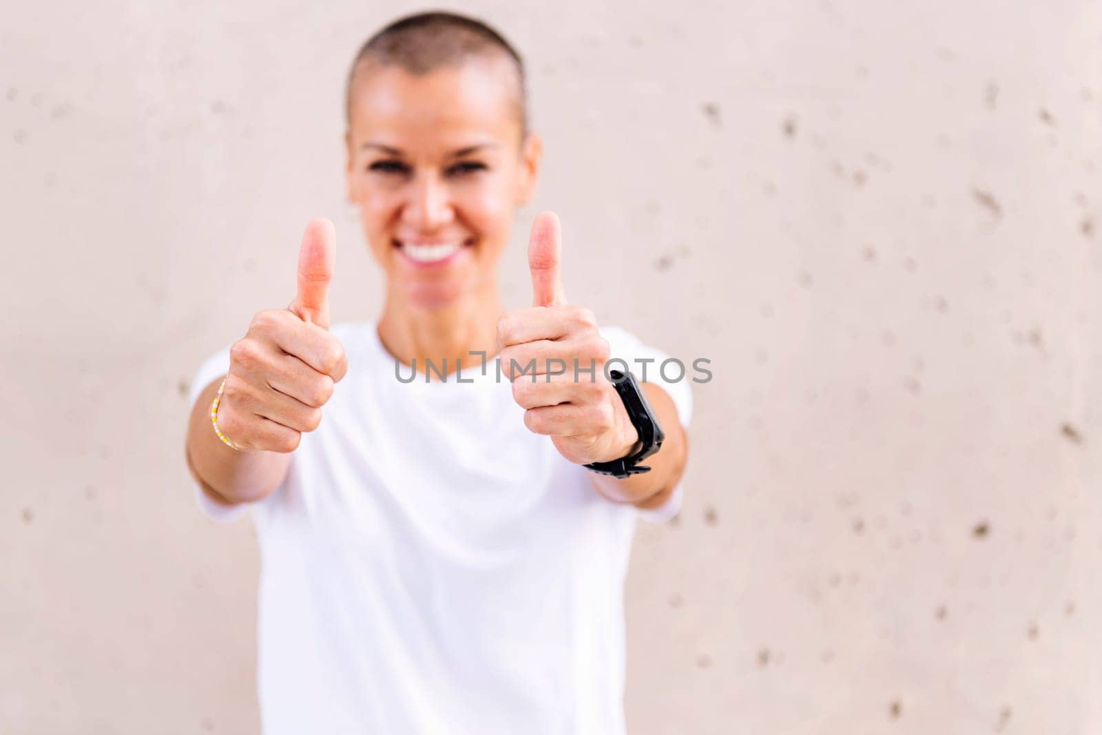 young woman with short hair smiling happy with with thumbs up looking at camera, copy space for text