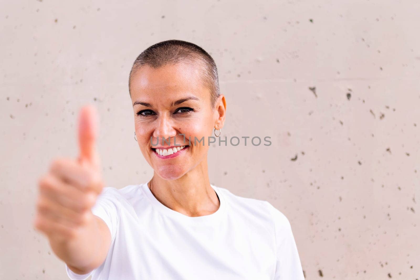 young woman with short hair smiling happy with with thumb up looking at camera, copy space for text