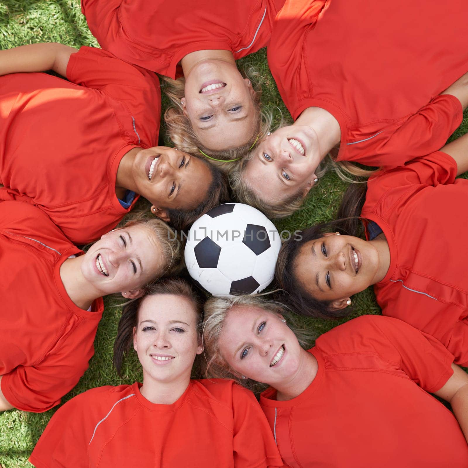 Happy woman, soccer ball and face of team above for unity, collaboration or synergy lying on green grass. Top view or portrait of female person, group or football players smile on outdoor field by YuriArcurs