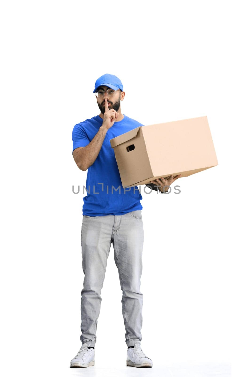 A male deliveryman, on a white background, in full height, with a box, shows a sign of silence by Prosto