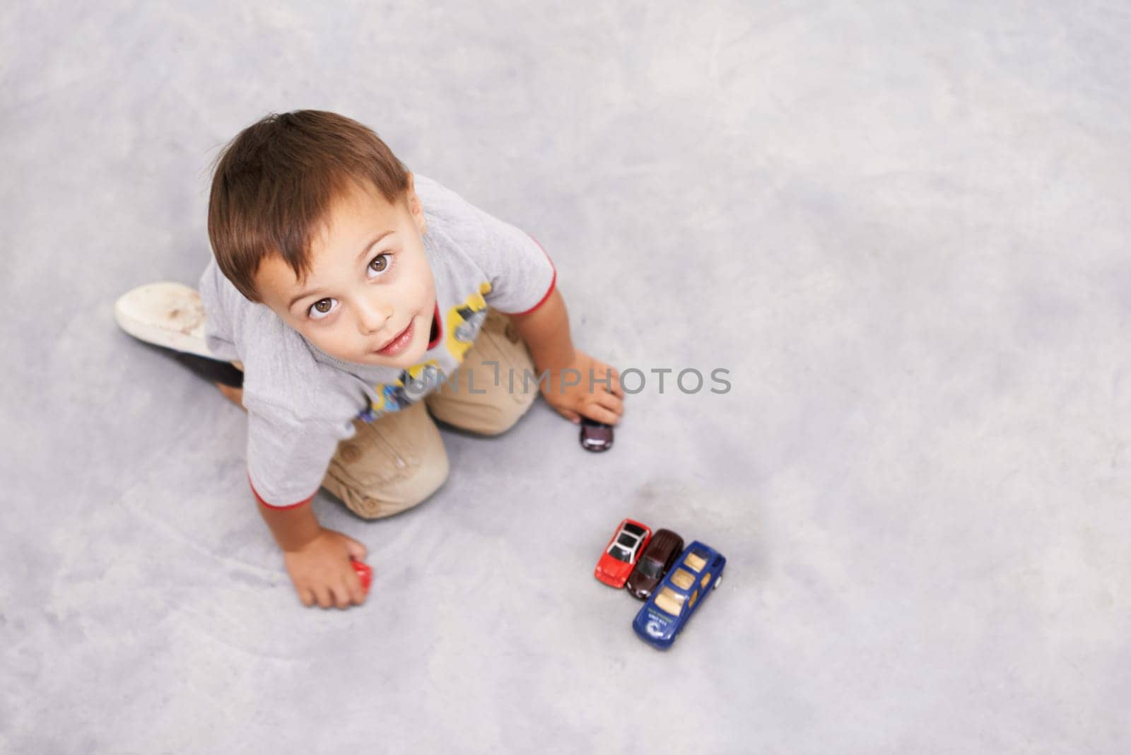 Car, toys and portrait of kid playing for learning, development and fun at modern home. Cute, top view and sweet young boy child enjoying game with vehicles on floor for childhood hobby at house