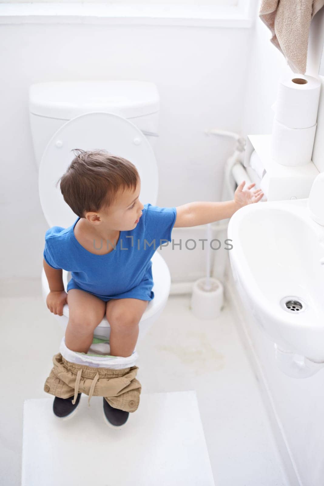 Boy child, potty training and toilet paper with sitting, diaper and thinking for learning, development or progress. Kid, family home and back in bathroom with tissue, hygiene or solution with nappy by YuriArcurs