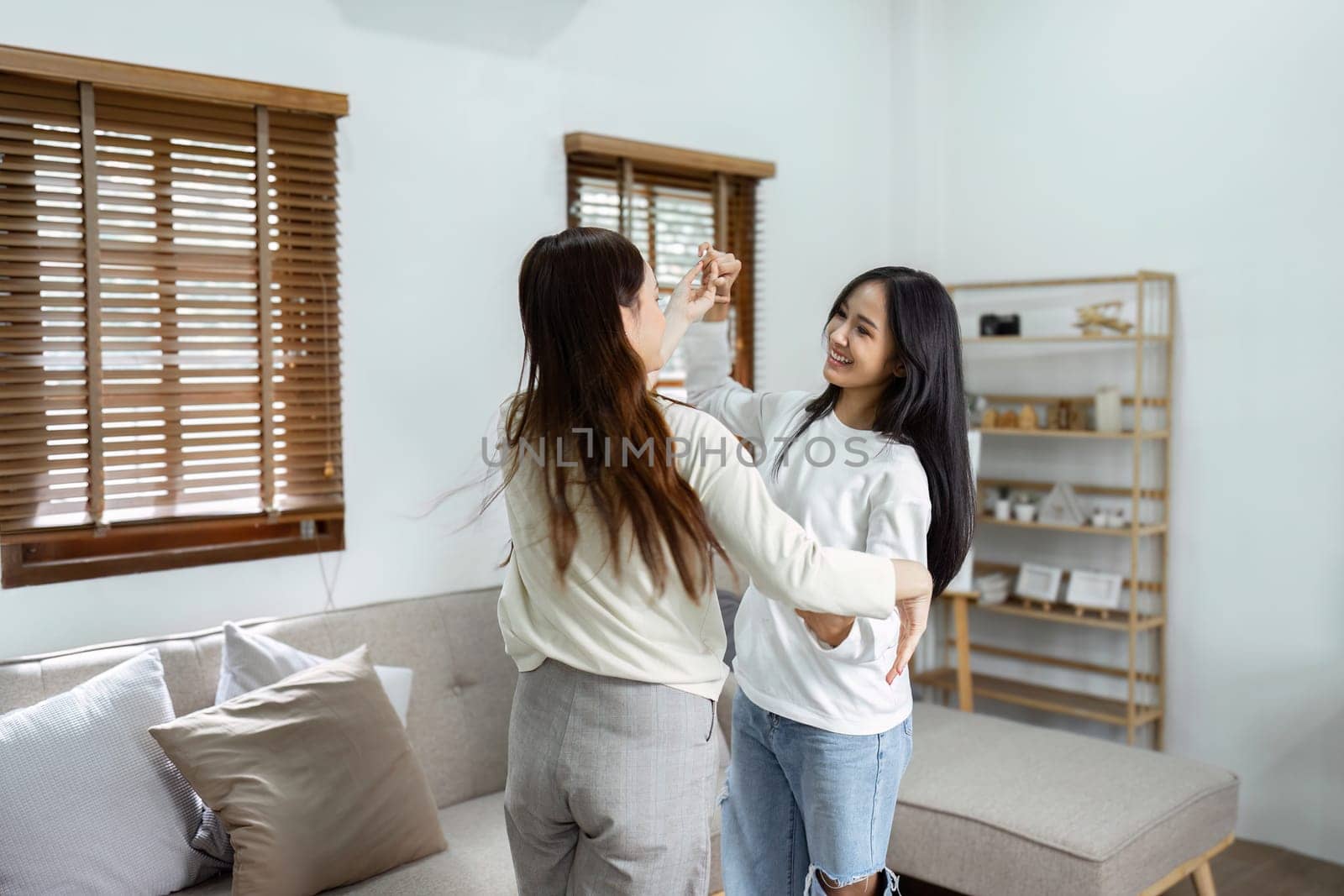 Young lesbian romantic couple in love dancing spending time together at home by itchaznong