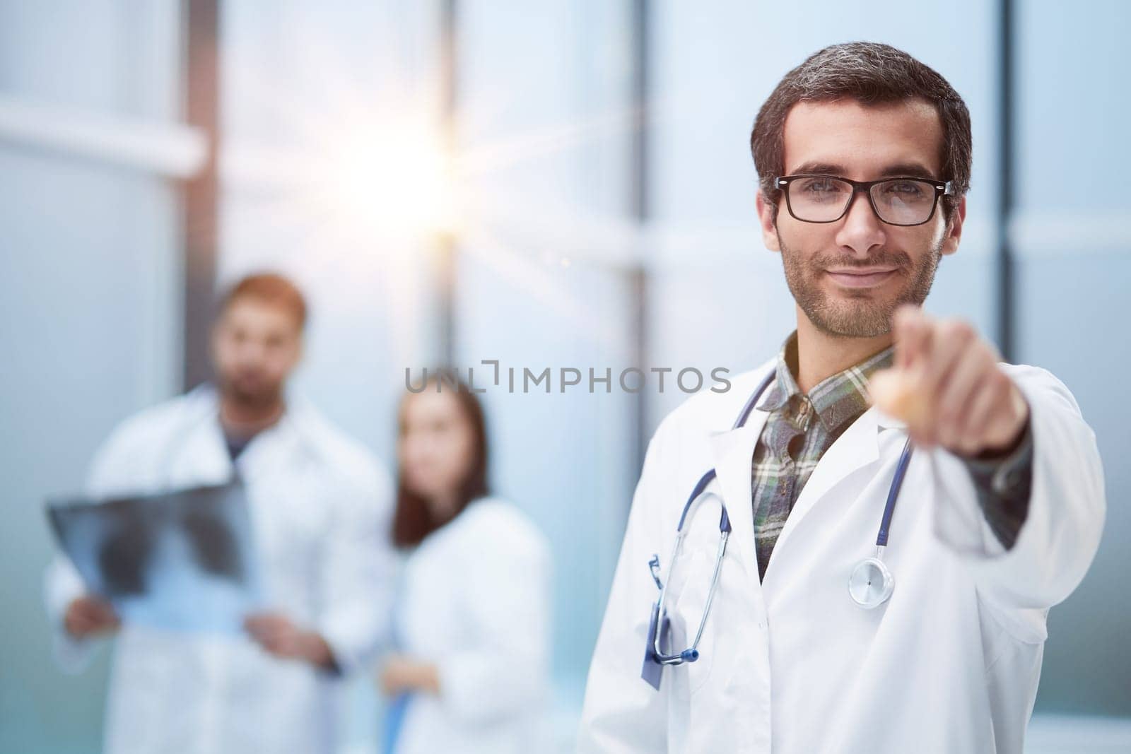 Young doctor man pointing with finger to the camera and to you, hand sign by Prosto