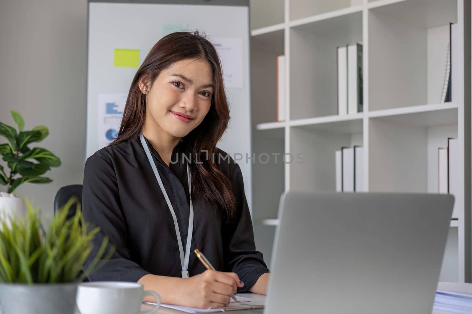 Portrait of young Asian woman working on laptop in modern office Perform accounting analysis, report investment data. Financial concepts and tax system.