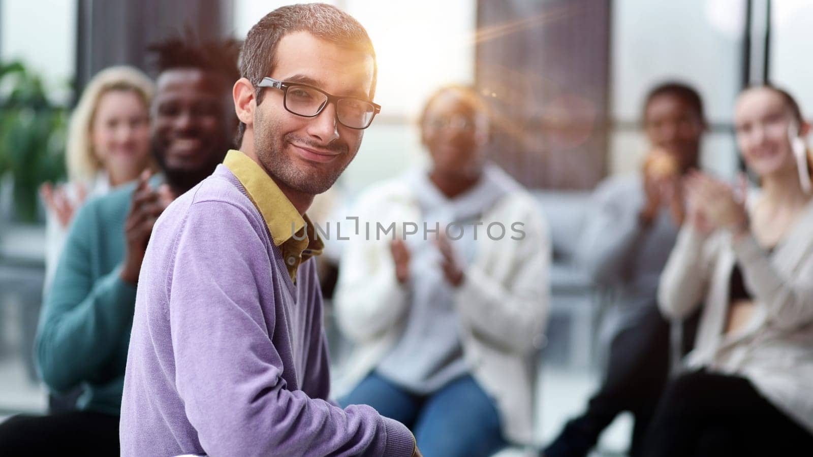 Young businessman sitting listening to trainer speaking to audience in trendy office