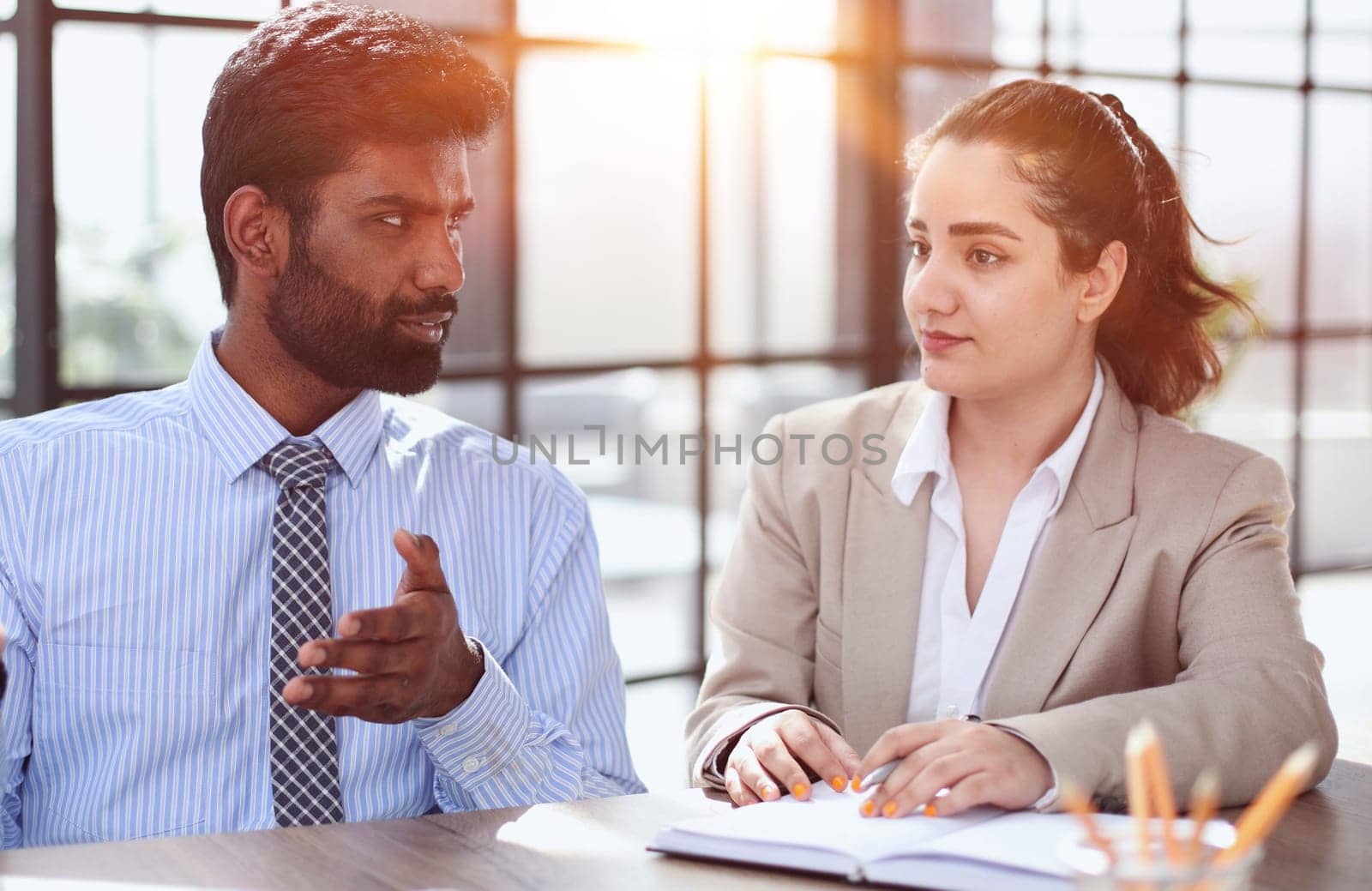 serious hindu manager helping colleague discuss new project in office