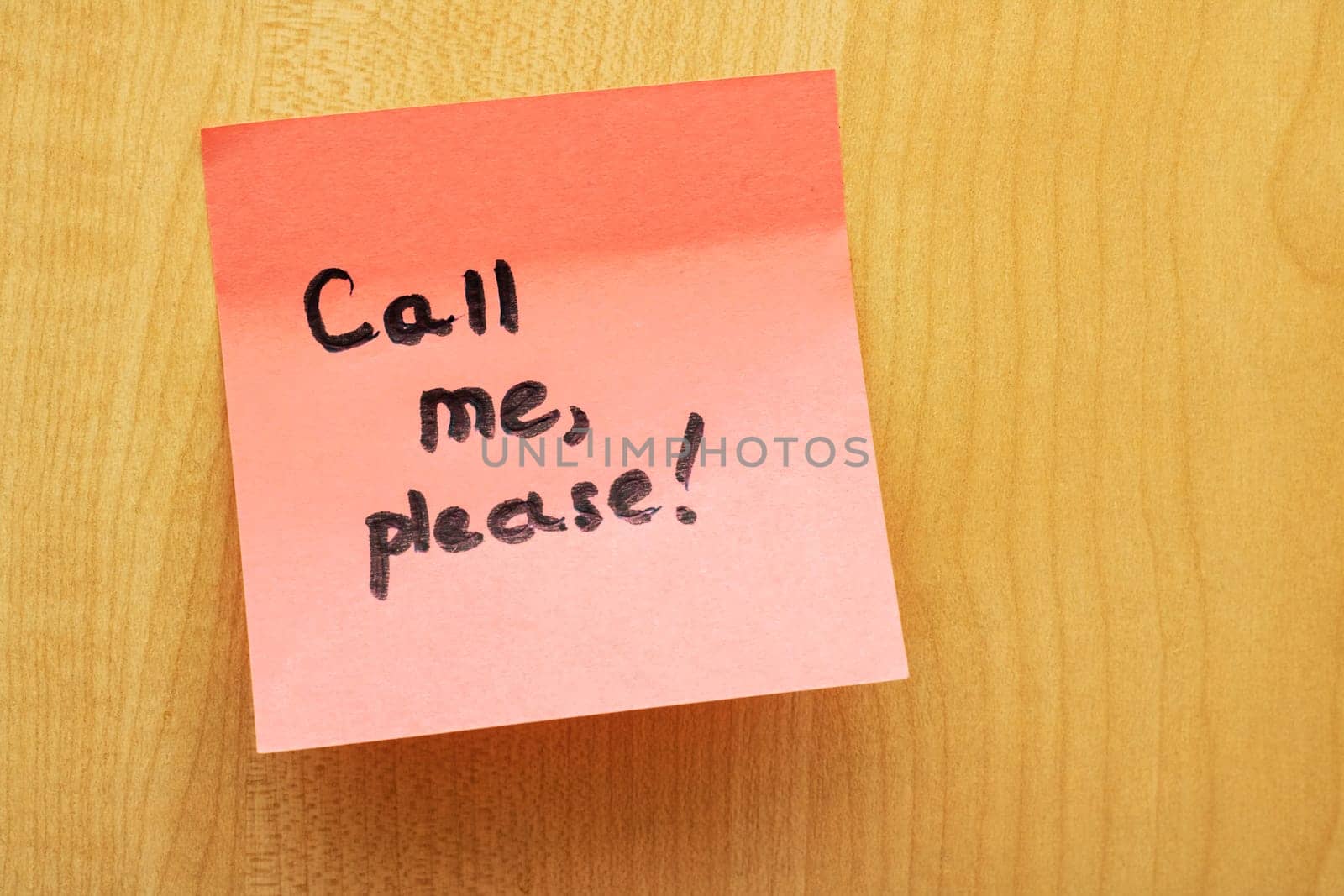 Pink paper sticker with the inscription Call me, please on wooden board