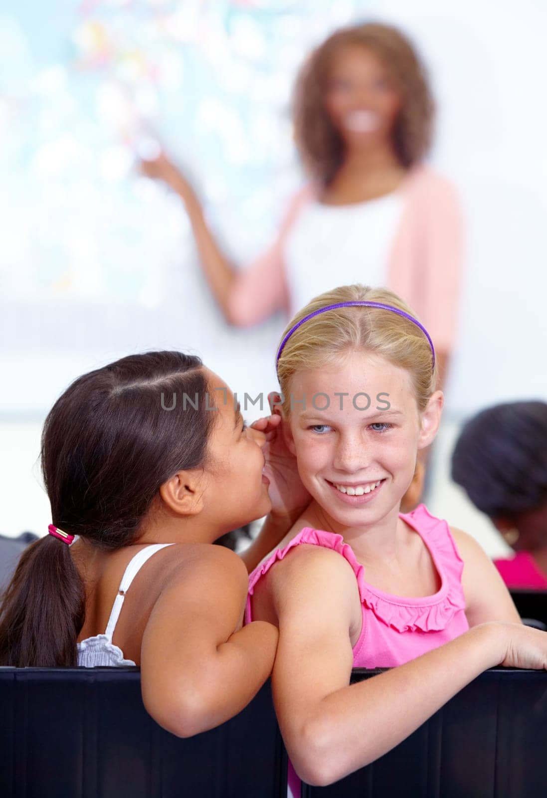 Little girls, whisper and classroom in ear for secret, gossip or communication in lesson at school. Children, students or friends listening to rumor, information or class together with teacher.