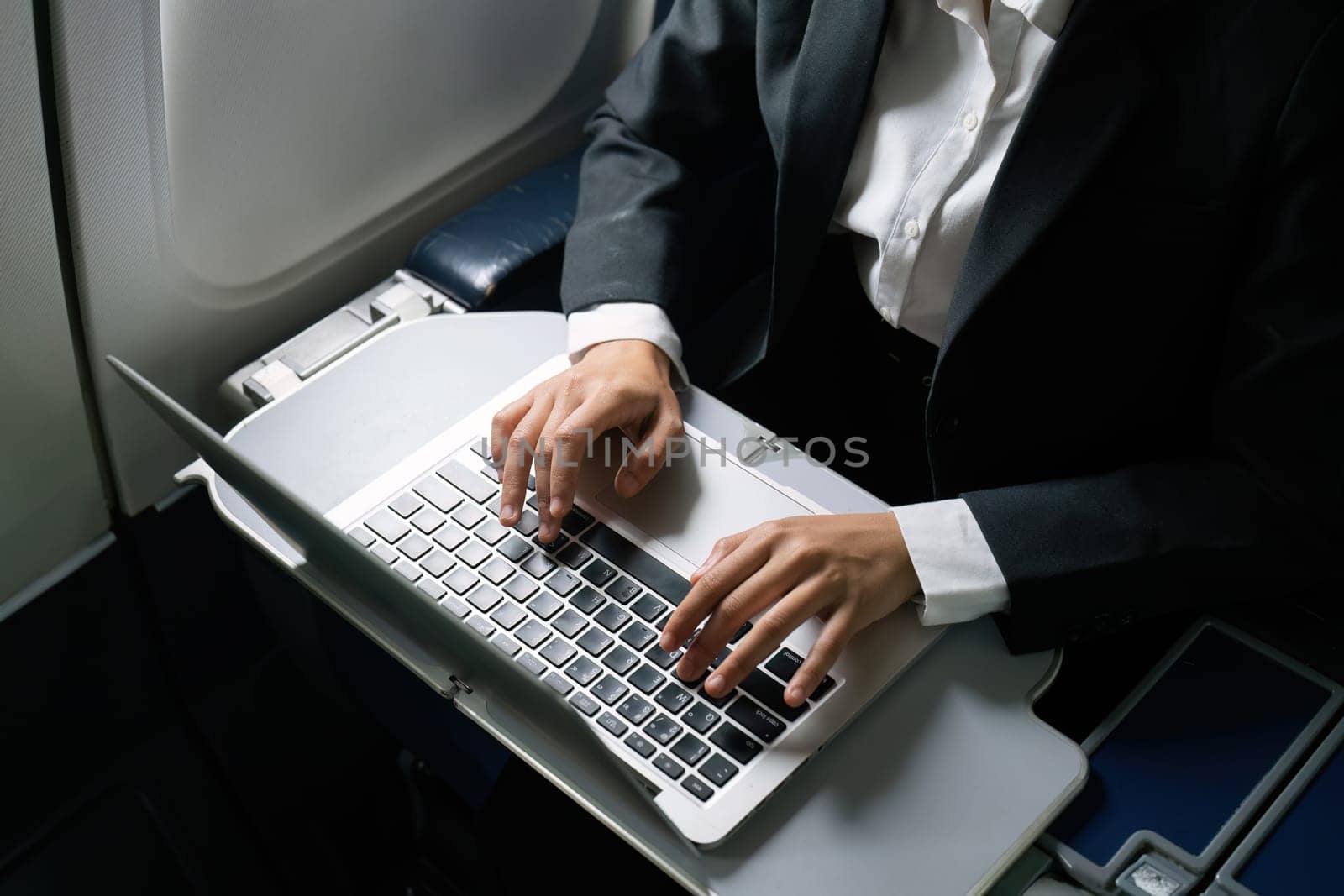 businesswoman flying and working in an airplane in first class, sitting inside an airplane using laptop.
