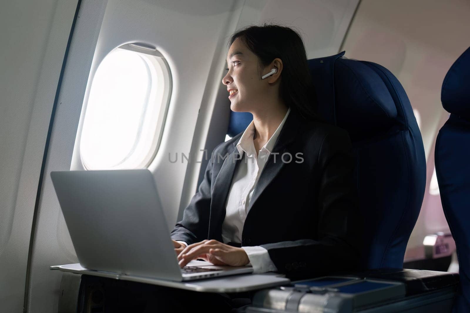 businesswoman flying and working in an airplane in first class, sitting inside an airplane using laptop.