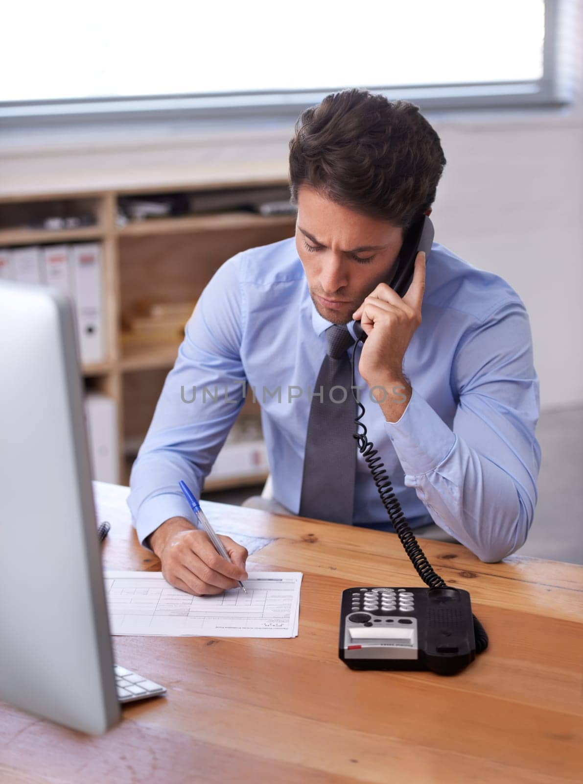 Business man, phone call and writing notes on landline in workplace, contact and consulting in office. Male professional, planning and communication or discussion, technology and connection for info.