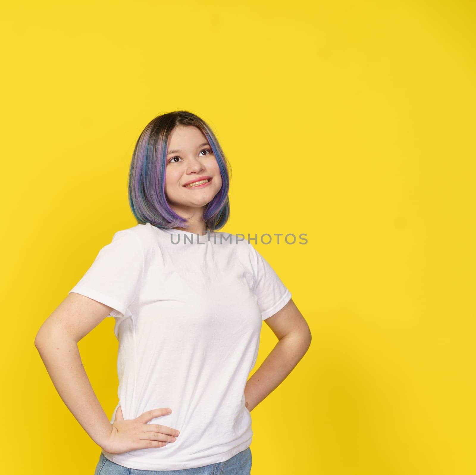 Happy Asian Teenager Girl, Dressed In White Shirt, Isolated Portrait On Yellow Background. Teenage Life, With Girl's Expressive Smile Creating Lively And Vibrant Atmosphere. Copy Space For Your Text. High quality photo