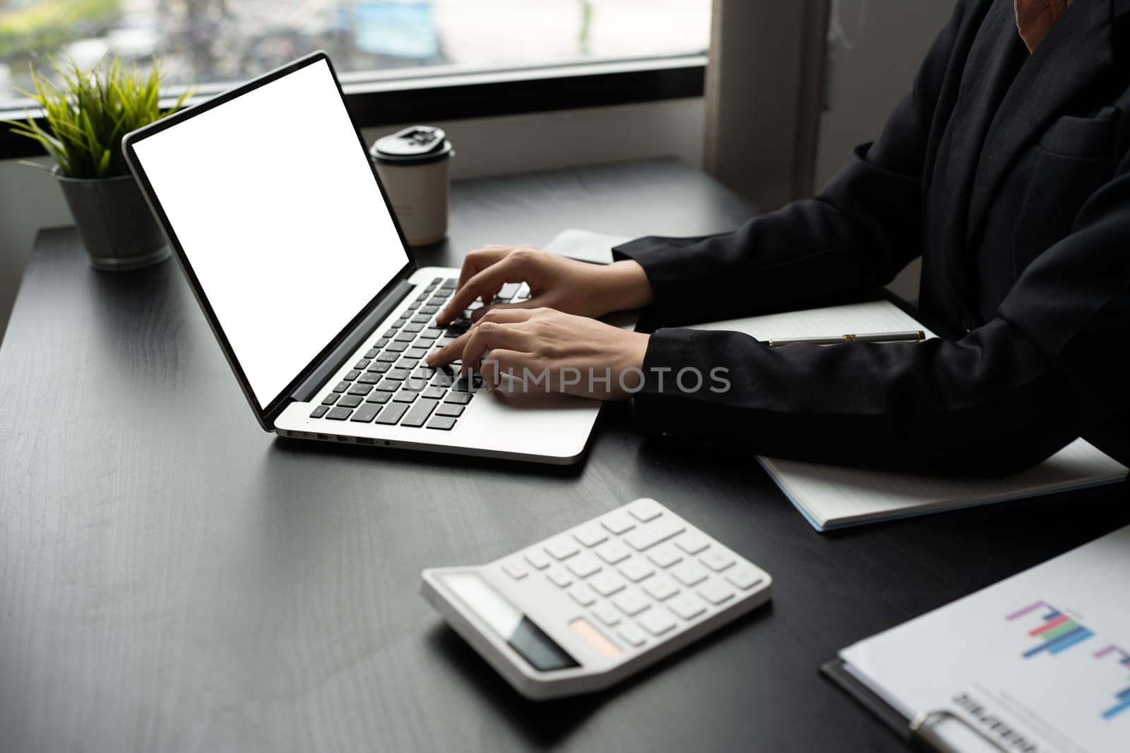 Mockup laptop, blank screen. Woman accountant using calculator and laptop in office.